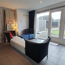 Helles Wohnzimmer in DE ZON IN STEE AAN ZEE in Serooskerke, Walcheren, mit gemuetlicher Sitzecke und Zugang zum Garten.