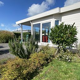 Buitenkant van Casa Mari chalet in Breskens, Zeeuws-Vlaanderen, omgeven door natuur en een uitnodigend terras voor ontspanning.
