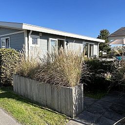 Vorderansicht von VZ808 Ferienhaus in Breskens mit gruenem Zaun, Zeeland.