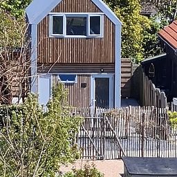Front view of Holiday home in Breskens, Zeeuws-Vlaanderen. Charming vacation home in Zeeland with wooden facade.