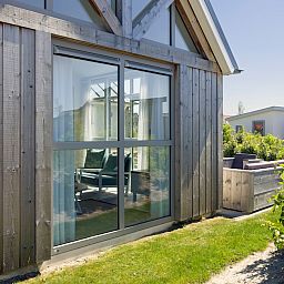 Gemuetliches Wohnzimmer im Ferienhaus L6B Comfort, Nieuwvliet-Bad, Zeeland, mit viel Licht und moderner Einrichtung.