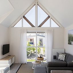 L6B Komfort-Ferienhaus in Nieuwvliet-Bad, Zeeland mit hellem Wohnzimmer und Gartenblick.