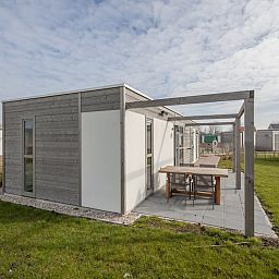 Geniessen Sie die moderne Veranda des Ferienhauses L4 Comfort in Nieuwvliet-Bad, Zeeuws-Vlaanderen, umgeben von gruener Natur.