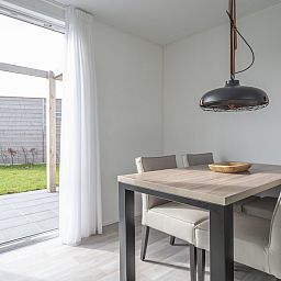 Stilvolles Esszimmer im Ferienhaus L4 Comfort, Nieuwvliet-Bad, mit Blick auf die Terrasse und den gruenen Garten in Zeeuws-Vlaanderen, Zeeland.