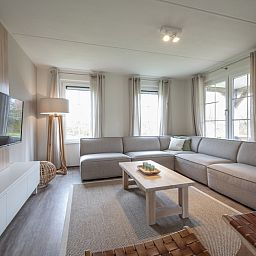 Stilvolles Wohnzimmer in Villa 10A Luxe, einem Ferienhaus in Cadzand-bad, Zeeuws-Vlaanderen, mit bequemen Sitzgelegenheiten und natuerlichem Licht.