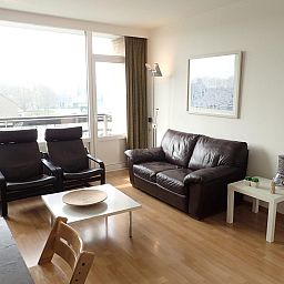 Gemuetliches Wohnzimmer der Ferienwohnung VZ922 in Cadzand, mit Ledersofa und grossen Fenstern fuer viel Licht.