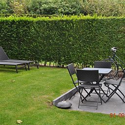 Tuin met ligstoelen bij VZ702 Vakantiehuis Cadzand in Cadzand, Zeeuws-Vlaanderen, perfect voor ontspanning.