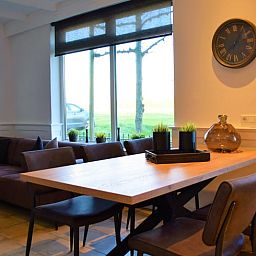 Stilvoller Innenraum des Ferienhauses in Schoondijke, Zeeuws-Vlaanderen, mit grossen Fenstern und einer gemuetlichen Sitzecke.