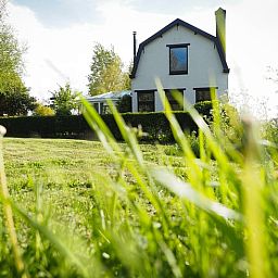 Vakantiehuis in Sluis, Zeeuws-Vlaanderen, omgeven door groene natuur en een uitgestrekt gazon, ideaal voor een ontspannen verblijf.