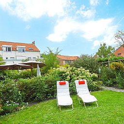 Garden of VZ052 Apartment Sluis in Sluis, Zeeuws-Vlaanderen with deck chairs and green surroundings.