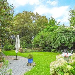 Cozy garden at VZ052 Apartment Sluis in Sluis, Zeeuws-Vlaanderen with parasol and seating area.