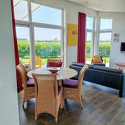 Innenansicht des Ferienhauses Waterresort Oosterschelde Haus Nr. 51, helles Esszimmer mit Blick auf den Garten in Wemeldinge, Zeeland.