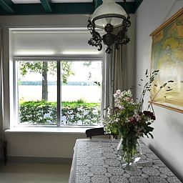 Binnenruimte van Vakantiehuisje in Lewedorp, Zuid-Beveland, met uitzicht op de natuur. Gezellige inrichting met bloemen en kaart aan de muur.