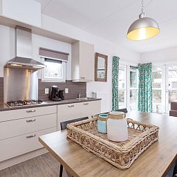 Moderne Kueche im Bungalow 6C, Ouddorp, Goeree-Overflakkee, Suedholland, mit heller Einrichtung und Blick auf die Terrasse.