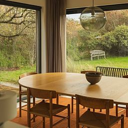 Gemuetlicher Essbereich im Ferienhaus in Ouddorp mit Blick auf den gruenen Garten, gelegen in Ouddorp, Goeree-Overflakkee, Suedholland.