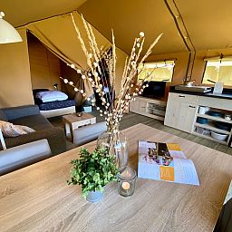 Gemuetlicher Innenbereich des Safaritent Zeeduin in Ouddorp, Goeree-Overflakkee, mit Kueche und Sitzecke in einer Glamping-Lodge.