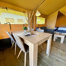 Innenbereich des Safarizeltes Zeeduin in Ouddorp, Goeree-Overflakkee. Gemuetliche Glamping-Lodge mit Holzboden und komfortablem Essbereich.