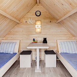 Gezellige binnenruimte van Kampeerhut 't Gorsje in Ouddorp met comfortabele bedden en houten inrichting.