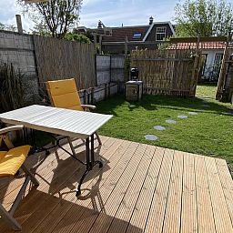 Blick von der Terrasse des Ferienhauses VZ991 in Ouddorp, mit gruenem Zaun.