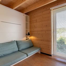Gezellige binnenruimte van ECO Cottage in Ouddorp, Zuid-Holland, met houten interieur en comfortabele zitbank, ideaal voor ontspanning.