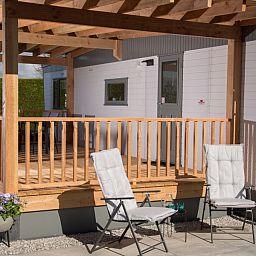 Sonnige Terrasse des Chalets Thuiz in Ouddorp, Suedholland, perfekt fuer das Leben im Freien und das Geniessen der Natur.