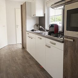 Moderne Kueche im Chalet Ouddorp, Ferienhaus in Ouddorp, Goeree-Overflakkee, Suedholland, mit schlichter Einrichtung und viel natuerlichem Licht.
