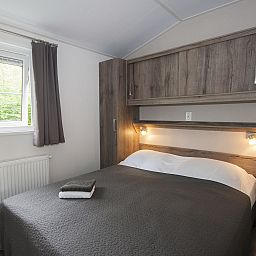 Gemuetliches Schlafzimmer im Chalet Ouddorp, einem Ferienhaus in Ouddorp, Goeree-Overflakkee, Suedholland, mit bequemem Bett und Holzinterieur.