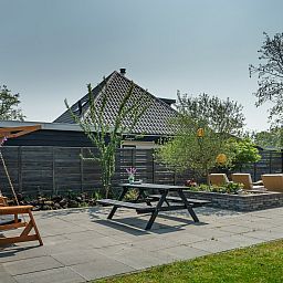 Gezellig terras met schommelstoel bij Vakantiewoning De Toekomst 107 'Siesta' in Ouddorp, perfect voor een ontspannen middag.