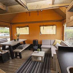 Gemuetlicher Innenbereich des Safarizeltes Duinroos in Ouddorp, Suedholland, mit bequemer Sitzecke und Holzinterieur.