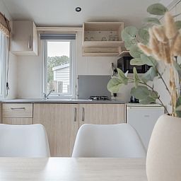 Innenbereich des Mobilheims der Kormoran in Ouddorp, Goeree-Overflakkee, mit moderner Kueche und Blick auf die Natur.