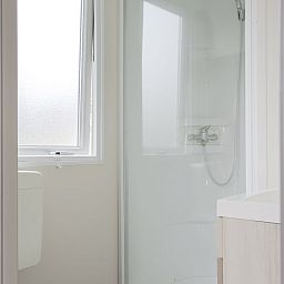 Modernes Badezimmer im Mobil home de Aalscholver, Mobil home in Ouddorp, Goeree-Overflakkee, Suedholland, mit eleganter Dusche und Fenster.