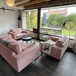 Gezellige woonkamer van VZ934 Bungalow in Ouddorp met uitzicht op de tuin in Zuid-Holland.
