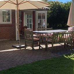 Terrasse des Ferienhauses in Goedereede mit Holzmoebeln und Sonnenschirm auf Goeree-Overflakkee.