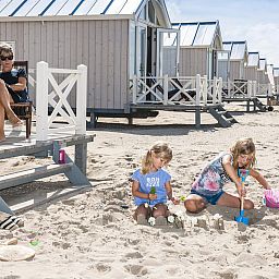 Geniessen Sie Entspannung im HaagseStrandhuisjes 5 pers in Den Haag. Kinder spielen am Strand vor diesem Ferienhaus an der Nordseekueste in Suedholland.