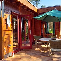 Terras van Vakantiehuisje in Groesbeek met parasol en zitplaatsen, ideaal voor ontspanning in Gelderland.