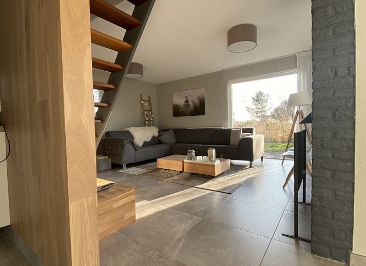 Veranda van Luxe 8 persoons Golf Villa Texel in De Cocksdorp met comfortabele stoelen en uitzicht op de groene tuin, perfect voor ontspanning.