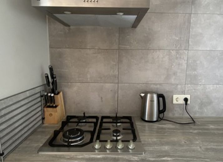 Veranda van Luxe 8 persoons Golf Villa Texel in De Cocksdorp met comfortabele stoelen en uitzicht op de groene tuin, perfect voor ontspanning.