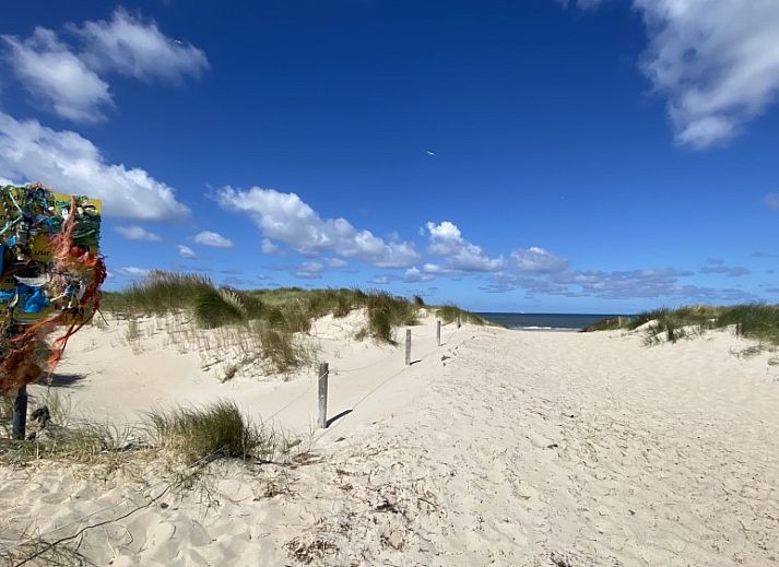 Gezellige woonkamer van Luxe 8 persoons Golf Villa Texel in De Cocksdorp met grote ramen en uitzicht op de tuin, perfect voor familiebijeenkomsten.