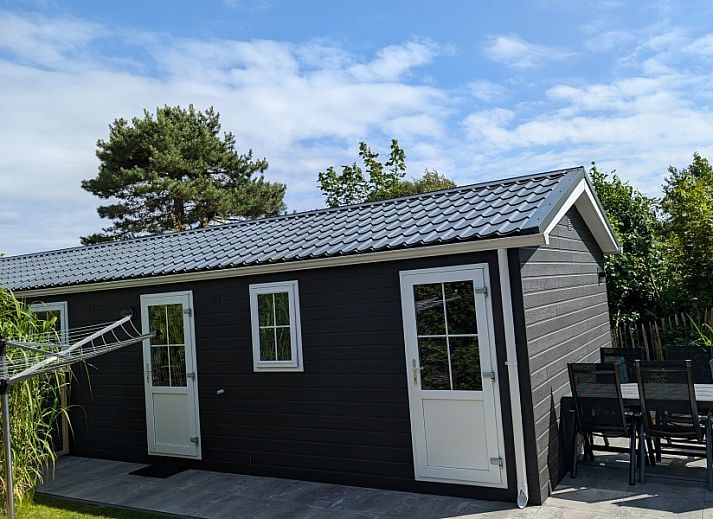 Ingang van Chalet 114 in De Cocksdorp, Texel, met een uitnodigend terras en groene omgeving op de Waddeneilanden.