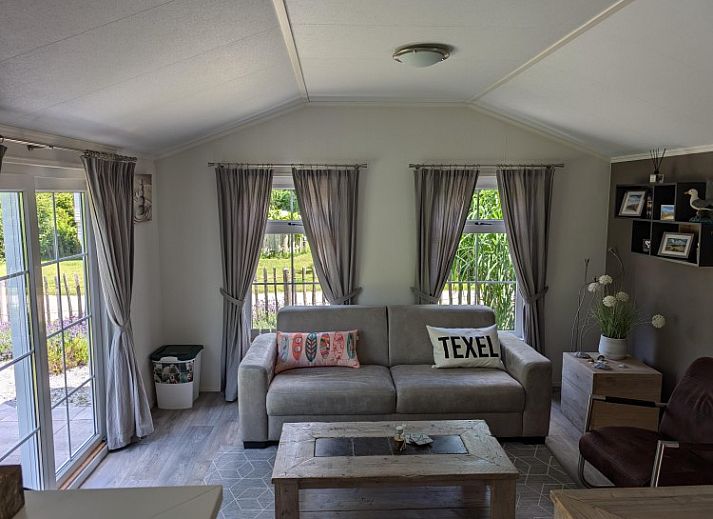 Vooraanzicht van Chalet 114 in De Cocksdorp, Texel, omgeven door weelderige tuinen op de Waddeneilanden.