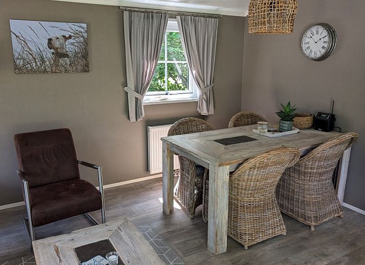 Vooraanzicht van Chalet 114 in De Cocksdorp, Texel, omgeven door weelderige tuinen op de Waddeneilanden.