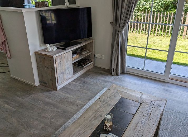 Vooraanzicht van Chalet 114 in De Cocksdorp, Texel, omgeven door weelderige tuinen op de Waddeneilanden.