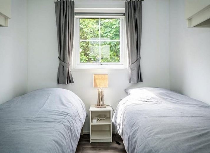 Vooraanzicht van Chalet 114 in De Cocksdorp, Texel, omgeven door weelderige tuinen op de Waddeneilanden.