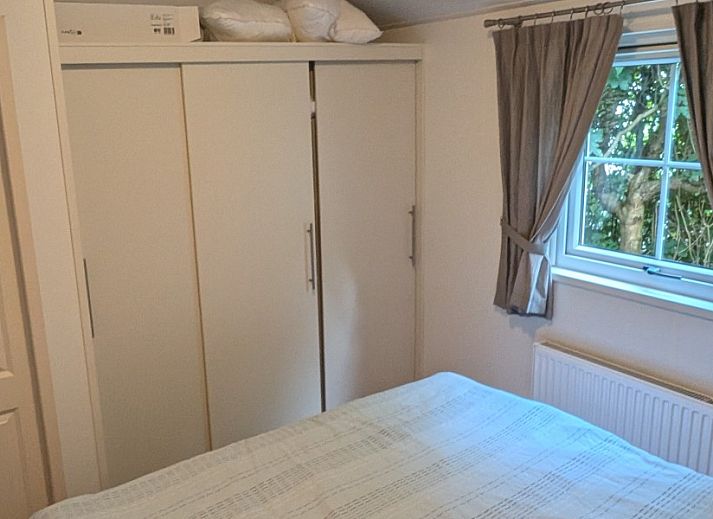 Vooraanzicht van Chalet 114 in De Cocksdorp, Texel, omgeven door weelderige tuinen op de Waddeneilanden.