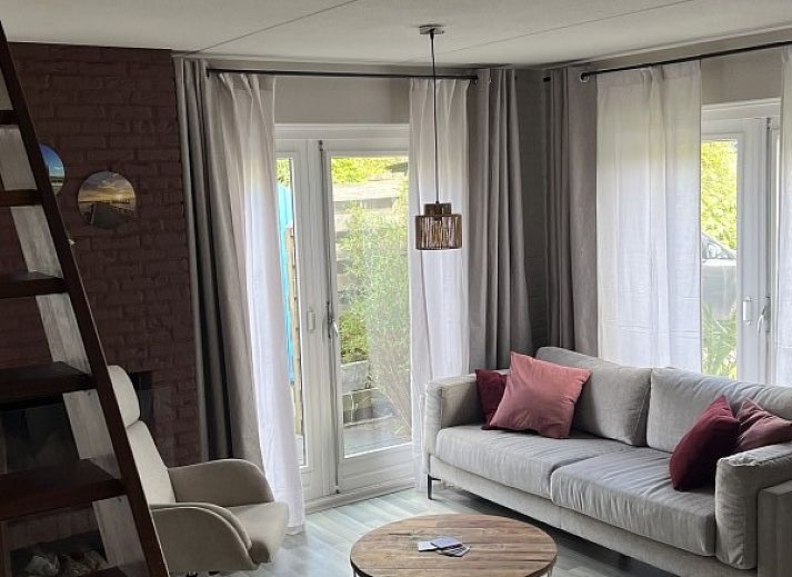 Gezellige woonkamer van TXL Huisje 299 in De Cocksdorp, Texel met comfortabele zithoek en toegang tot het terras.