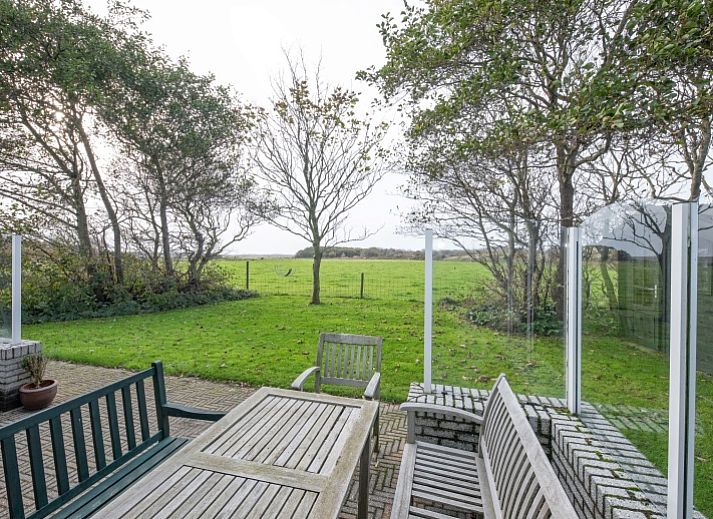Gezellige woonkamer in Vakantiehuis Schelpenoord 129, De Cocksdorp, Texel, met comfortabele zitruimte en uitzicht op groene omgeving.
