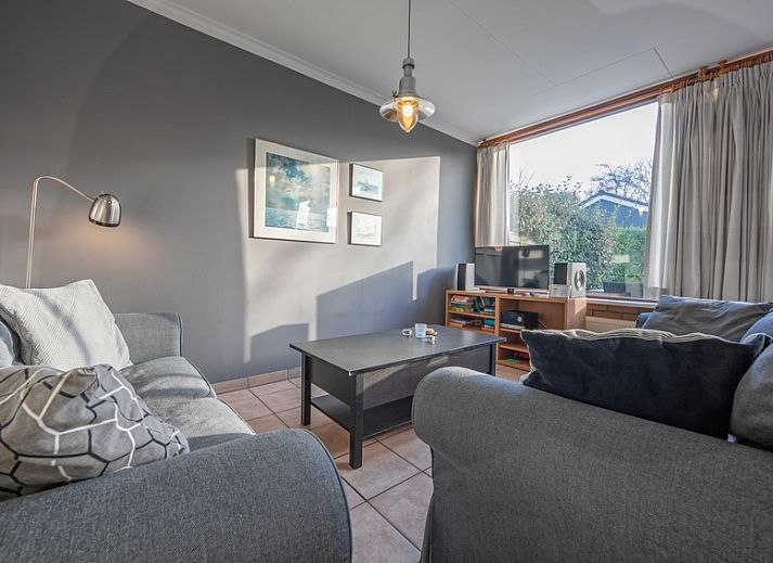 Geniet van het zonnige terras bij Vakantiehuis Slufterhoek 114 in De Cocksdorp, Texel, met comfortabele zitplaatsen en parasol.