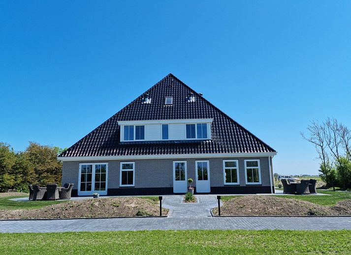 Vakantiehuis De Slufter in De Cocksdorp, Texel biedt een prachtig uitzicht op de natuur met een serene vijver en groene omgeving.