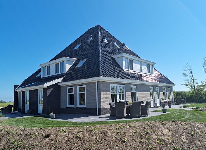 Vakantiehuis De Slufter in De Cocksdorp, Texel biedt een prachtig uitzicht op de natuur met een serene vijver en groene omgeving.