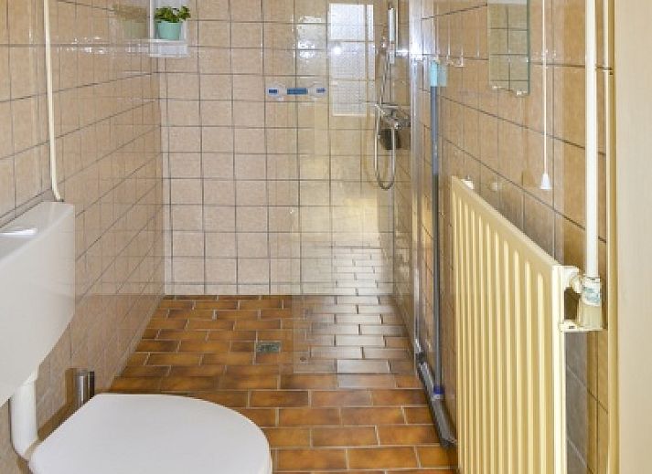 Terrace of vacation home Duinviooltje in De Cocksdorp, Texel with wooden bench and garden table.